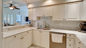 A kitchen with white cabinets, a marble countertop, a ceiling fan, and a coffee maker. - Waterfront Punta Gorda Condo w/ Pool Access! (Punta Gorda)