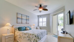 A bedroom with a bed, nightstands, a desk, a ceiling fan, a window, and artwork on the wall. - Waterfront Punta Gorda Condo w/ Pool Access! (Punta Gorda)