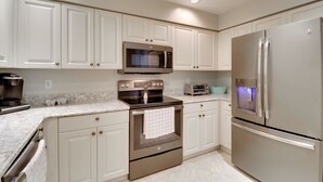 A modern kitchen with white cabinets, stainless steel appliances, and a marble countertop. - Waterfront Punta Gorda Condo w/ Pool Access! (Punta Gorda)