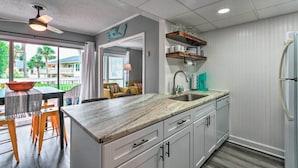A modern kitchen with a large island, white cabinetry, and a view of the outdoors.
