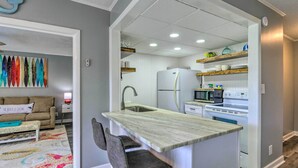 A compact kitchen with a central island, white appliances, and a dining area with a sofa and chairs.
