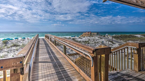 A wooden boardwalk leading to a beach with a wooden structure in the distance.