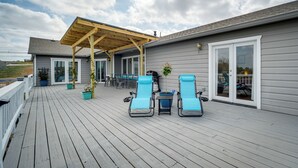 Une terrasse couverte avec deux chaises longues bleues, une table et des plantes en pot.