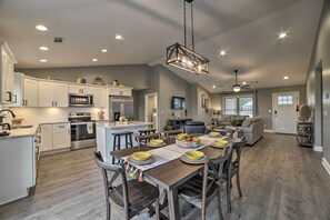 A spacious kitchen with white cabinets, a central island, and a dining area with a wooden table and chairs. - Cozy Murray Retreat Near MSU & Local Eateries (Murray)