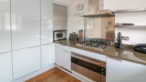 A modern kitchen with white cabinets, a built-in oven, a microwave, a gas stove, and a stainless steel range hood. - 30 Dart Marina (Dartmouth)