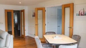 A modern dining area with a marble table and cushioned chairs, wooden doors, and a cityscape artwork on the wall. - 30 Dart Marina (Dartmouth)