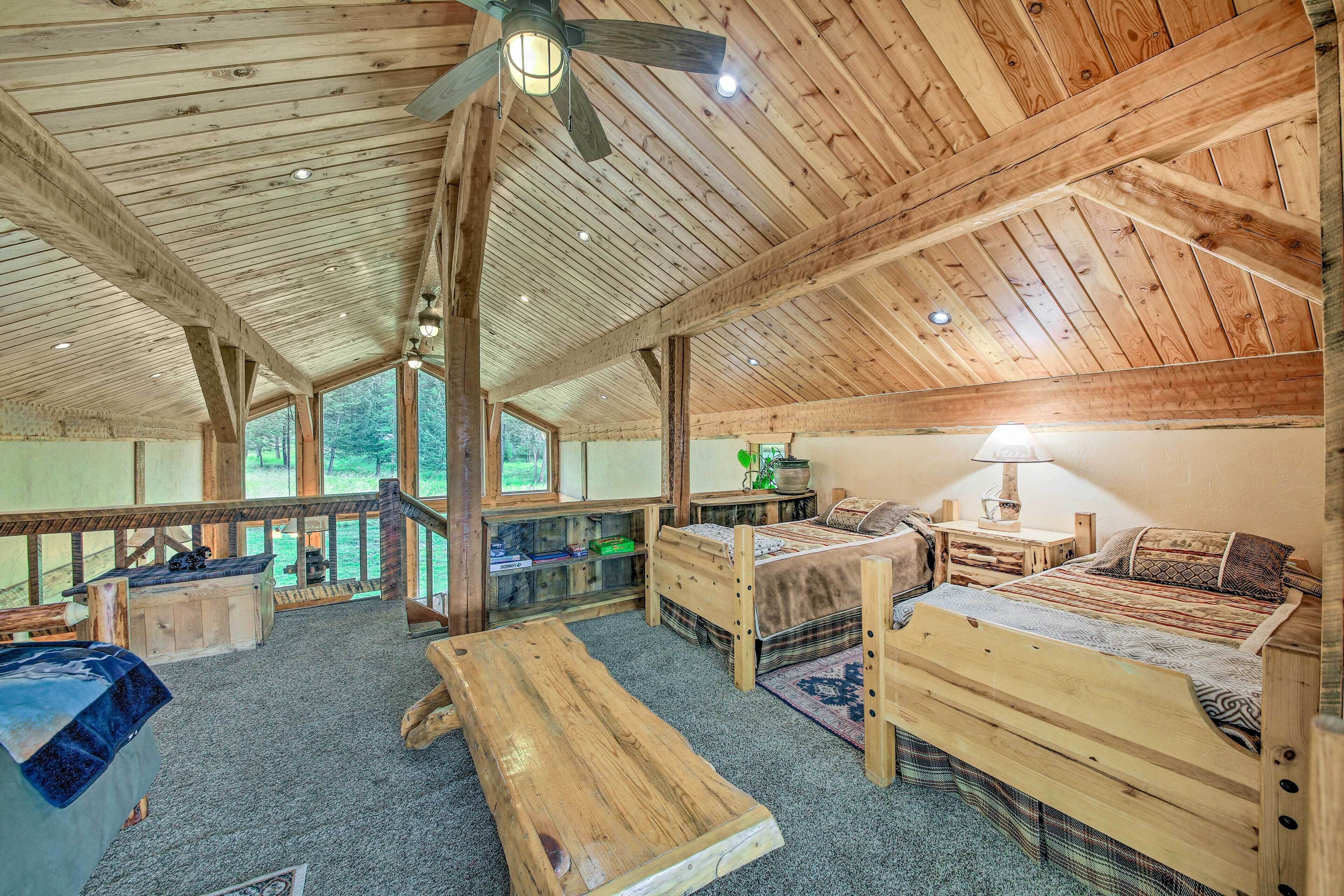 A rustic wooden cabin interior with a loft bed, a wooden bench, and a dining table.