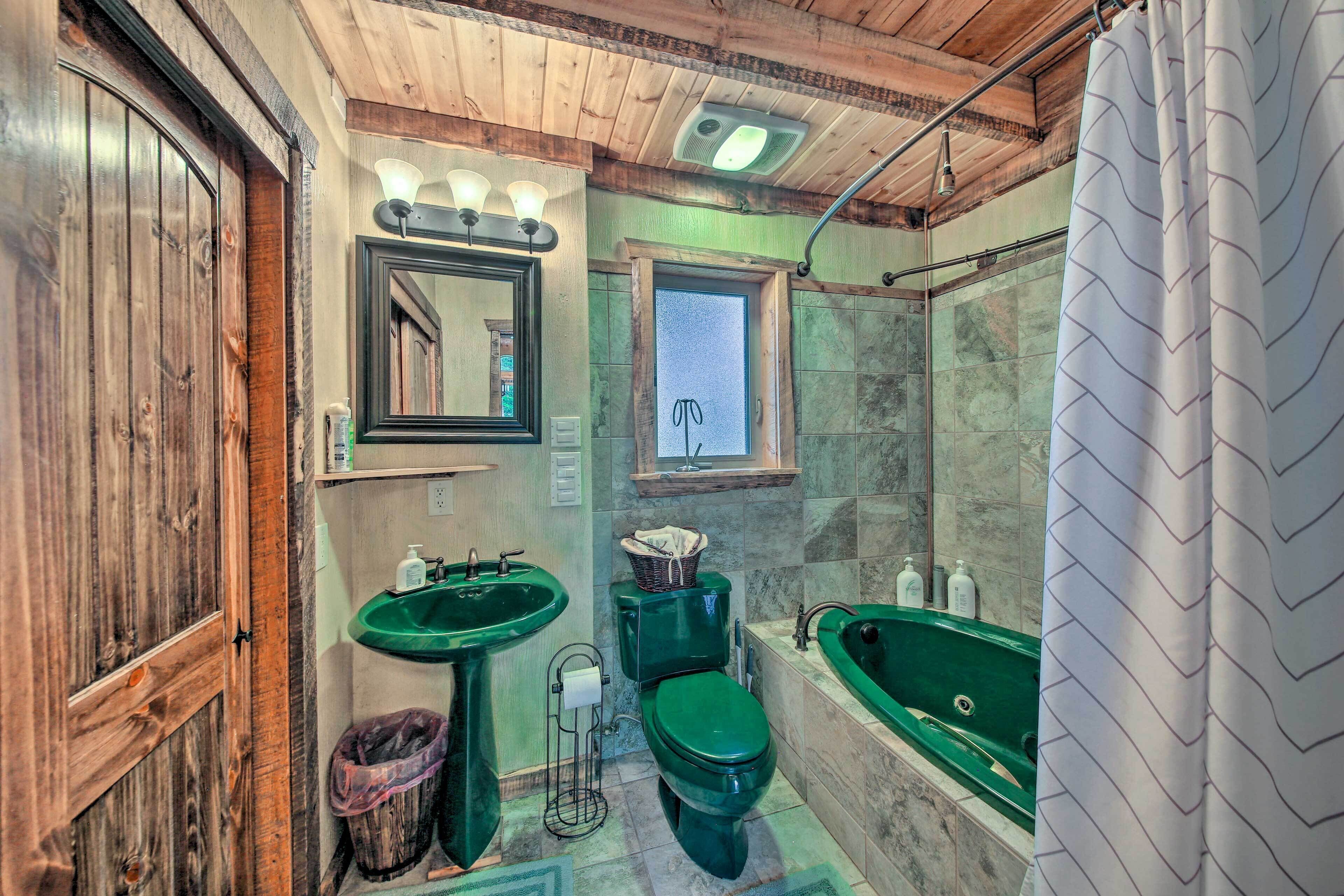 Un baño con techo de madera, lavamanos verde, inodoro y bañera.