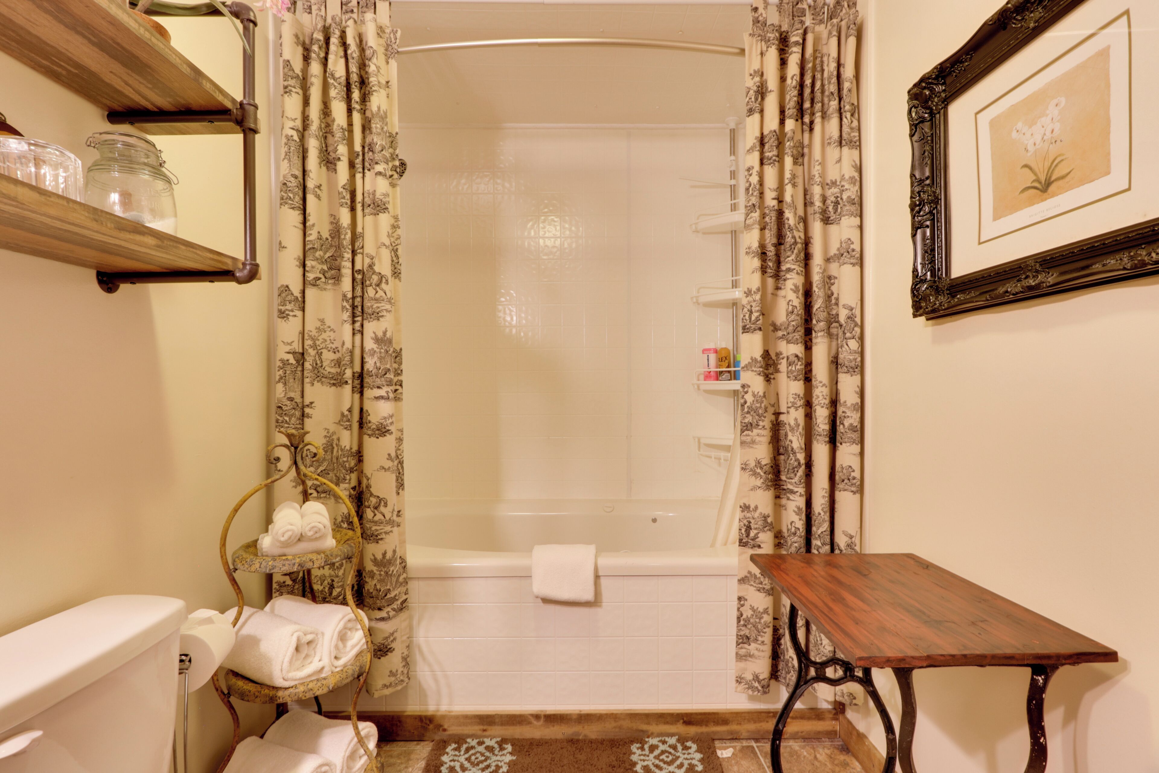 Une salle de bain avec une douche, des toilettes et une petite table en bois.