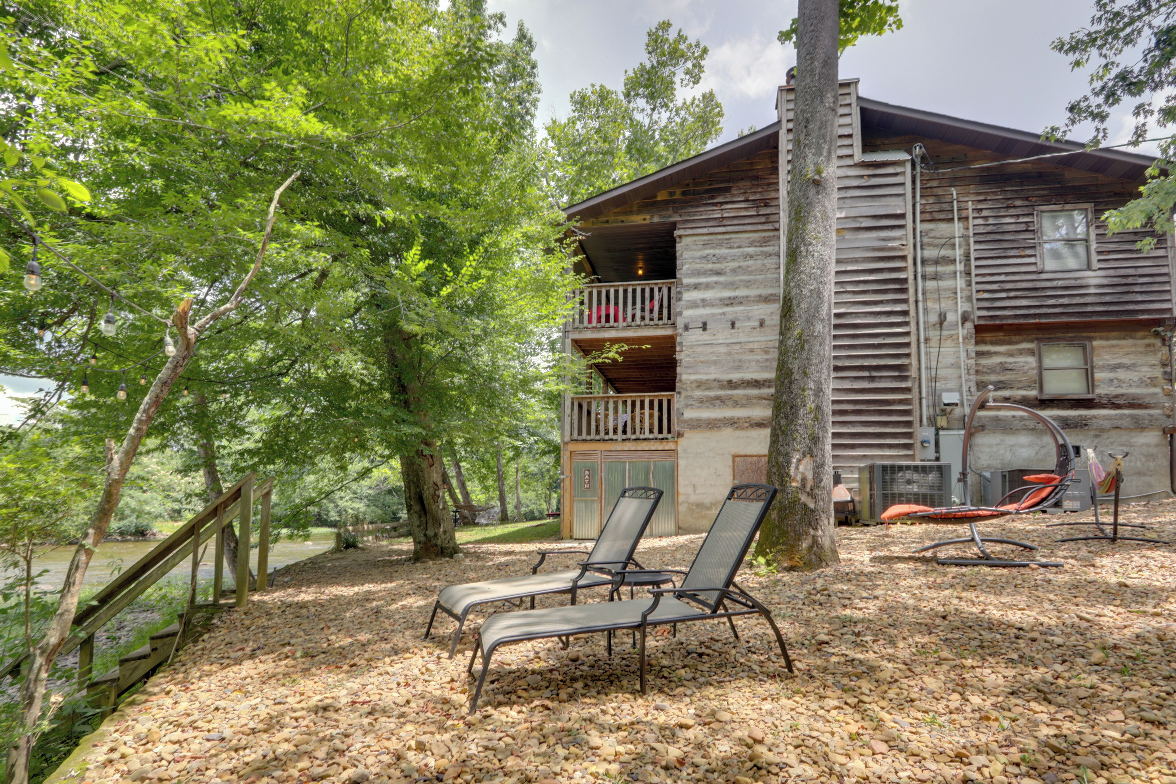 A rustic cabin with a balcony, two lounge chairs, and a hammock.