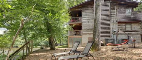 A rustic cabin with a balcony, two lounge chairs, and a hammock.