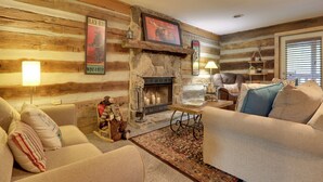 A cozy living room with a stone fireplace, wooden walls, and a comfortable sofa. - Riverfront Couple's Retreat in Smoky Mountains! (Townsend)
