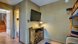 Ein Zimmer mit einem Holzkoffer, einem Wand-Fernseher und einem Etagenbett.