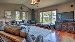 Ein geräumiges Wohnzimmer mit Ledersofas, einem Kamin, einem großen Fernseher und einer Steinwand.