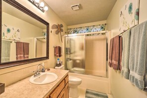A bathroom with a large mirror, a sink, a toilet, and a shower.