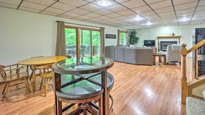 Un salon spacieux doté d’un plancher en bois, d’une table à manger avec un plateau en verre et d’un canapé.