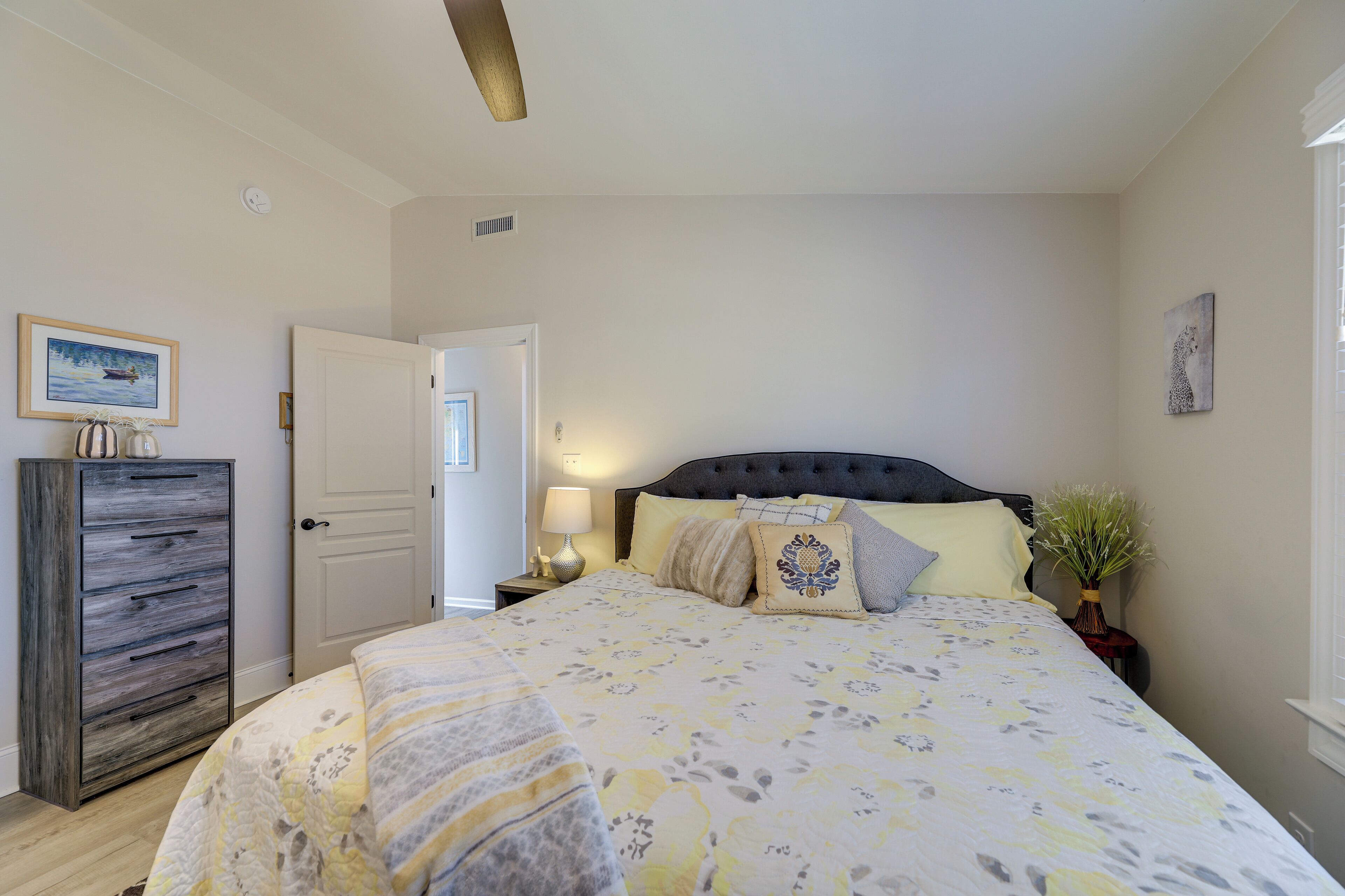 Une chambre à coucher avec un lit, une table de chevet, une lampe et une commode.