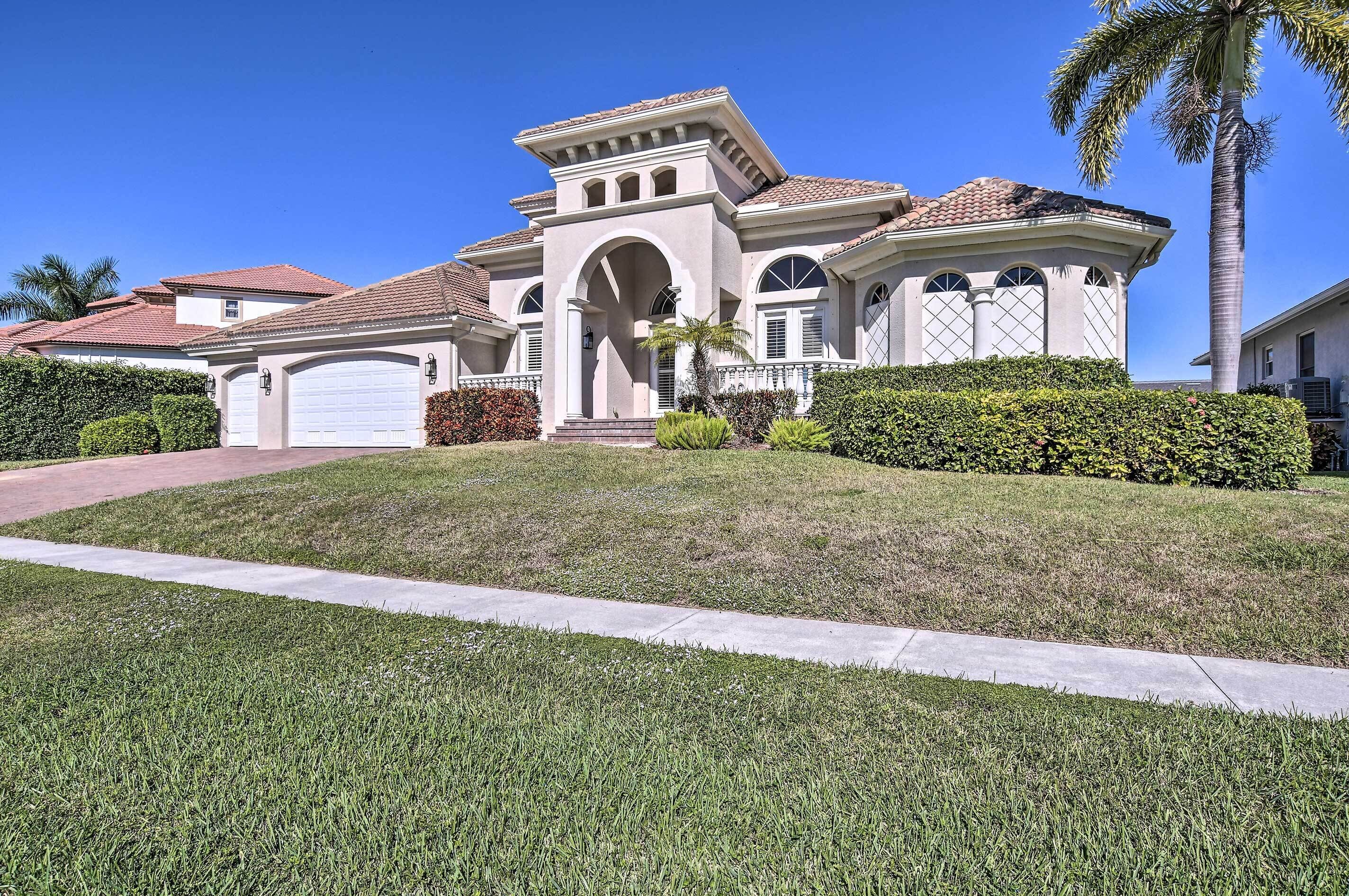 A large, single-story house with a prominent arched entrance, a tiled roof, and a well-maintained lawn.