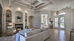 A spacious living room with a fireplace, a large sofa, and a dining area with a view. - Luxury Island Oasis w/ Pool & Dock, 1 Mi to Beach! (Marco Island)