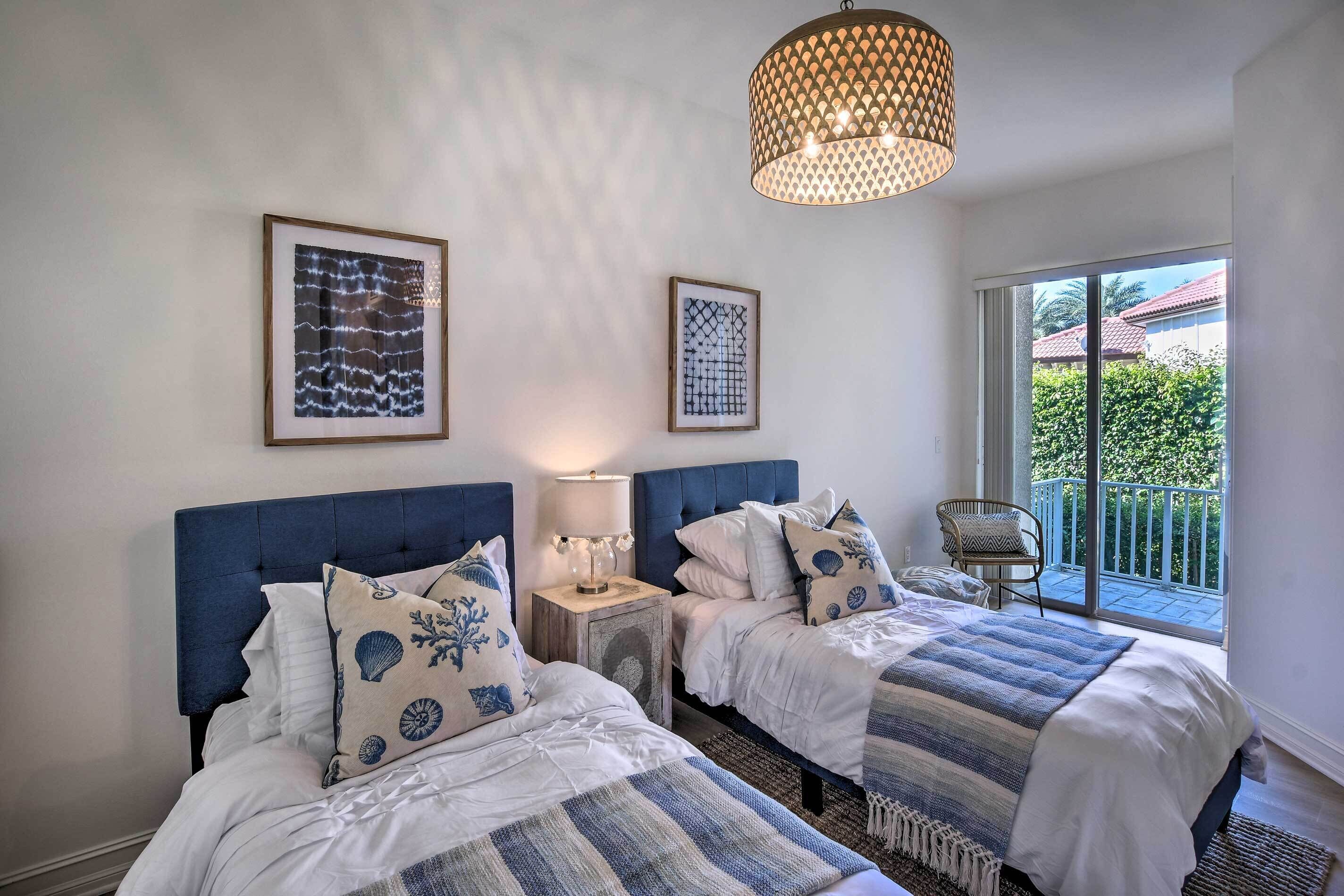 A bedroom with two beds, a chandelier, and a balcony with a view.