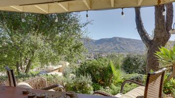 Relax in a serene outdoor space surrounded by lush greenery and distant mountains, with a table set for a fun game or activity.