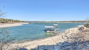 A riverside dock with a covered seating area and a sandy beach. - Covered Deck & 2-story Dock: Lake Travis Home! (Leander)