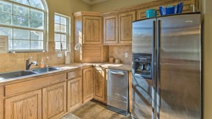 A kitchen with wooden cabinets, a stainless steel refrigerator, and a built-in oven. - Covered Deck & 2-story Dock: Lake Travis Home! (Leander)