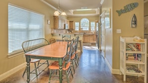 A spacious kitchen with a dining table and chairs, wooden cabinets, and a fish-themed wall decoration. - Covered Deck & 2-story Dock: Lake Travis Home! (Leander)