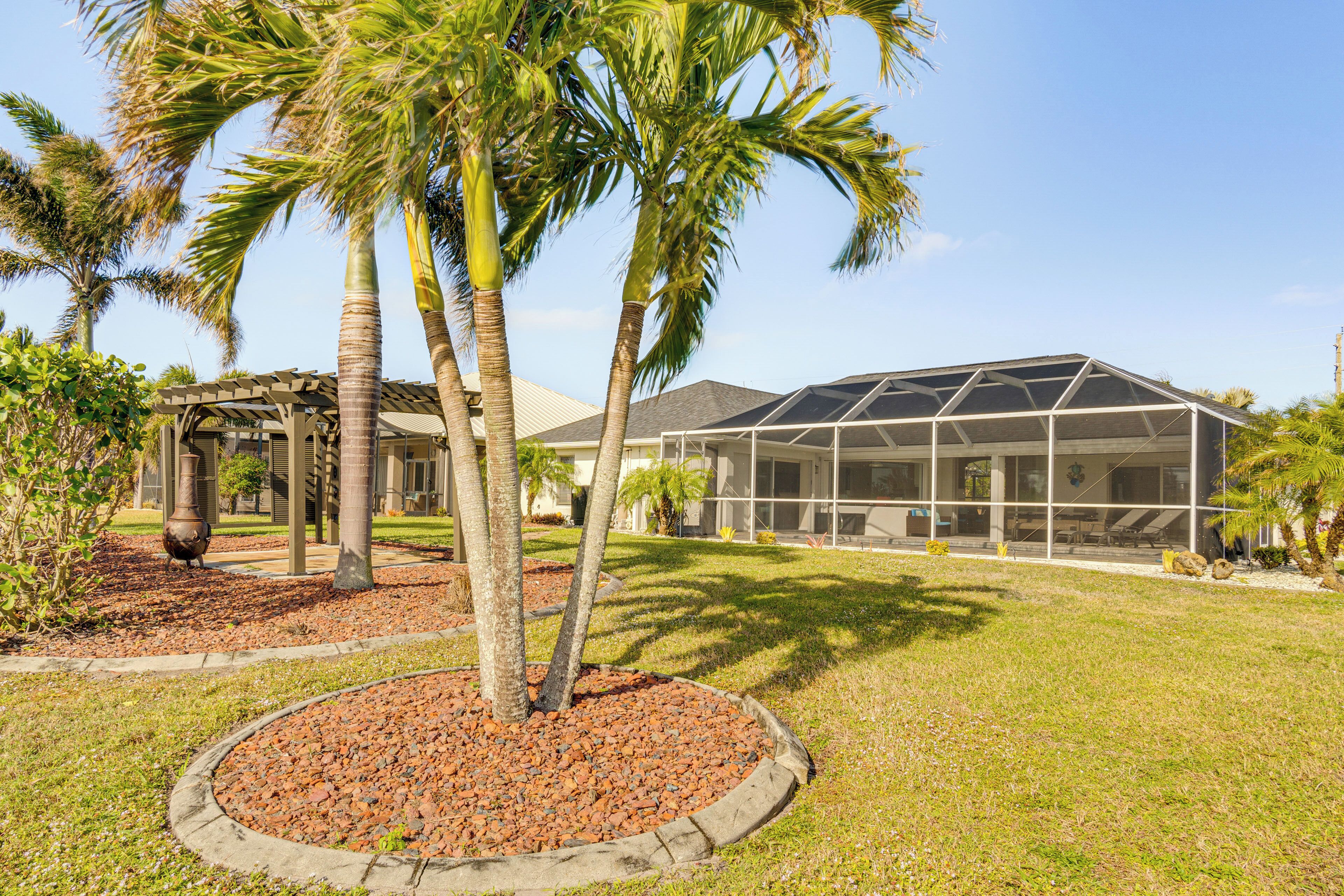 A modern building with a glass facade, surrounded by a well-maintained lawn and palm trees.