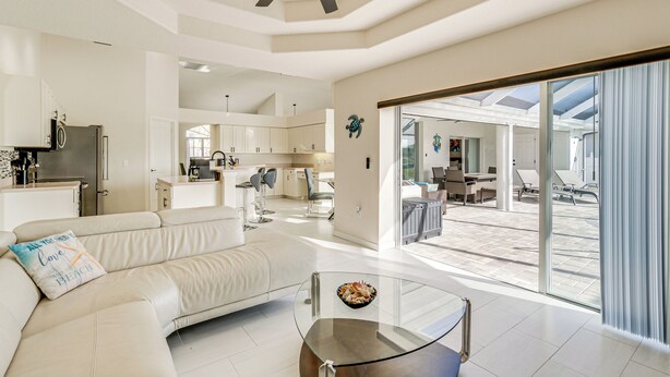 Uma sala de estar moderna com uma mesa de centro de vidro, um sofá bege e um ventilador de teto.