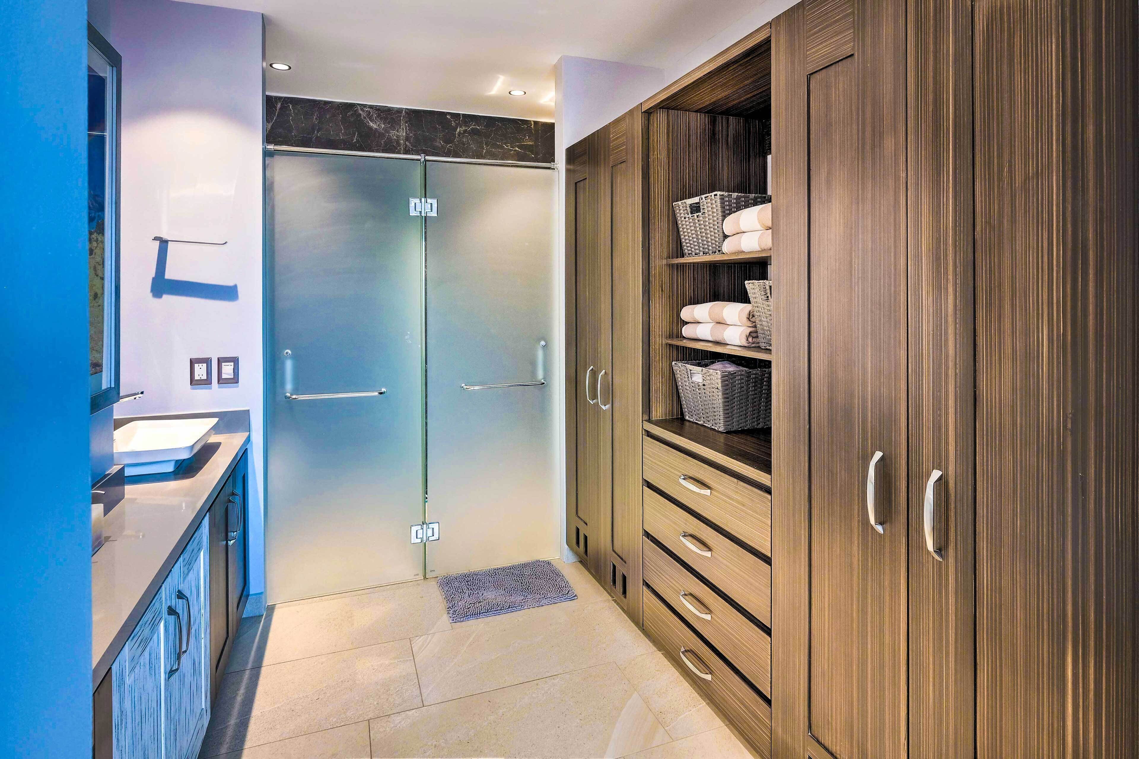 A modern bathroom with a glass shower, wooden cabinets, and a sink.