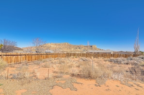 Un paysage désertique avec une clôture en bois, une végétation clairsemée et un bâtiment situé au loin.