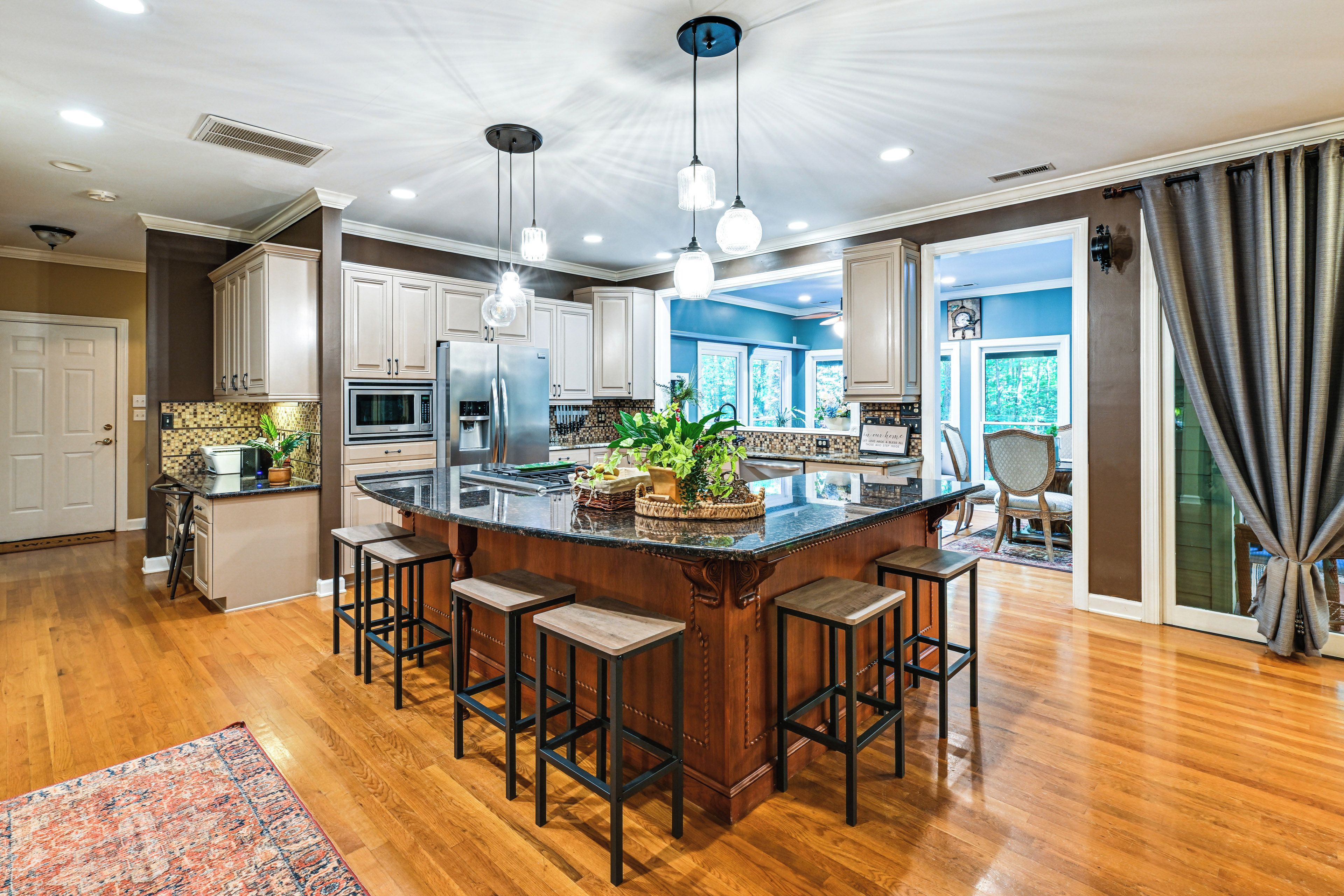 A spacious kitchen with a central island, bar stools, and a view of the dining area.