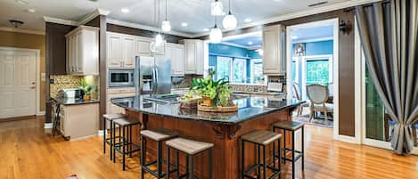 A spacious kitchen with a central island, bar stools, and a view of the dining area.