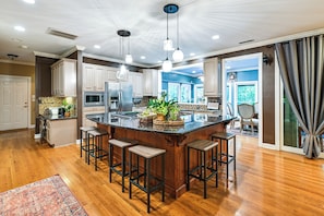 A spacious kitchen with a central island, bar stools, and a view of the dining area. - Lake Norman Cove Home w/ Golf Sim & Kayaks (Sherrills Ford)