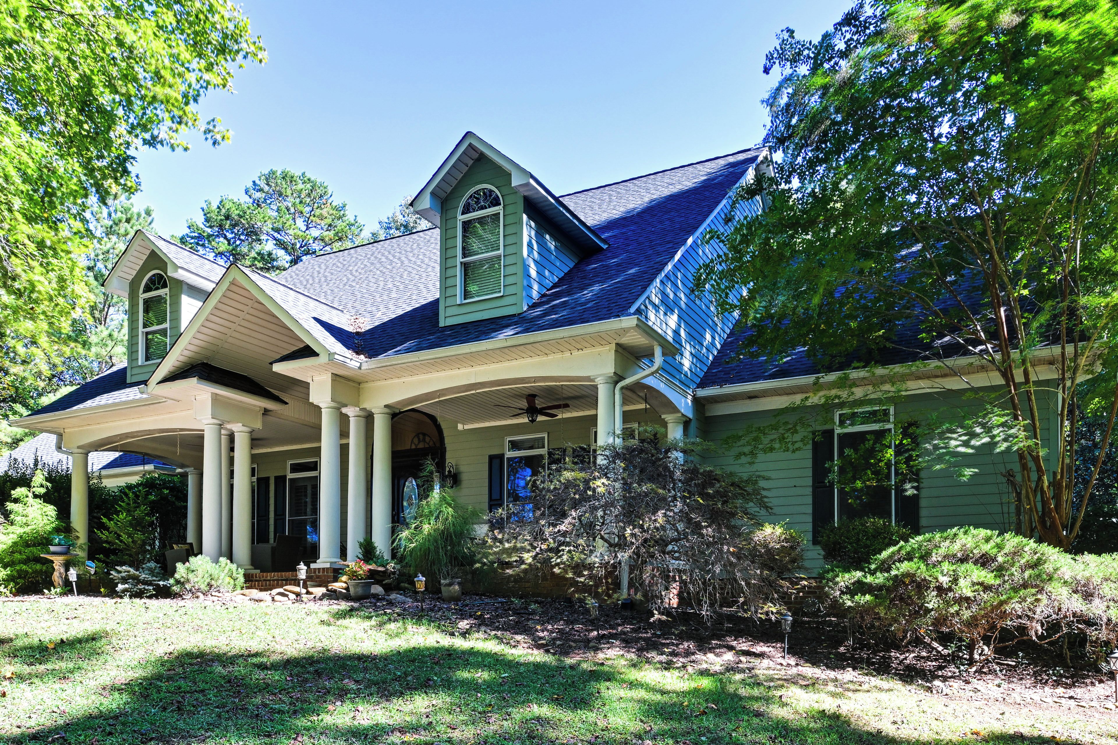 A two-story house with a covered porch, a steeply pitched roof, and a well-maintained garden.