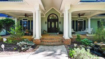 A house with a front porch, two columns, a black door, and a small garden.