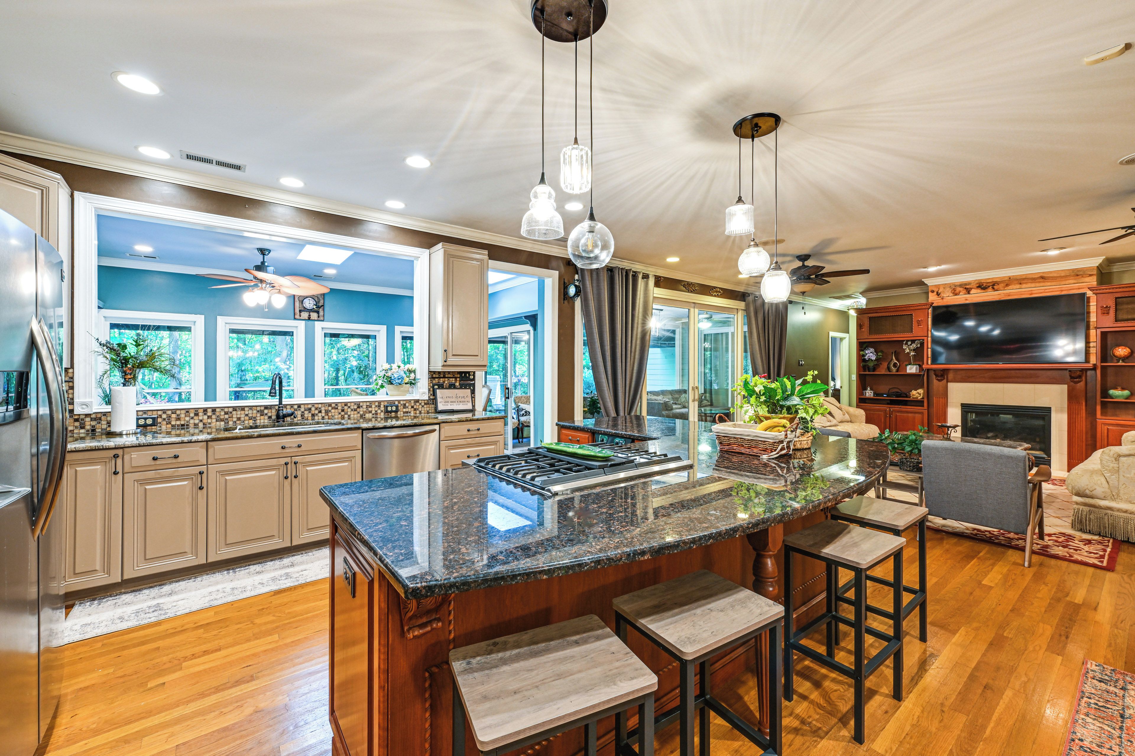 A spacious kitchen with a central island, bar stools, and a dining area with a fireplace.