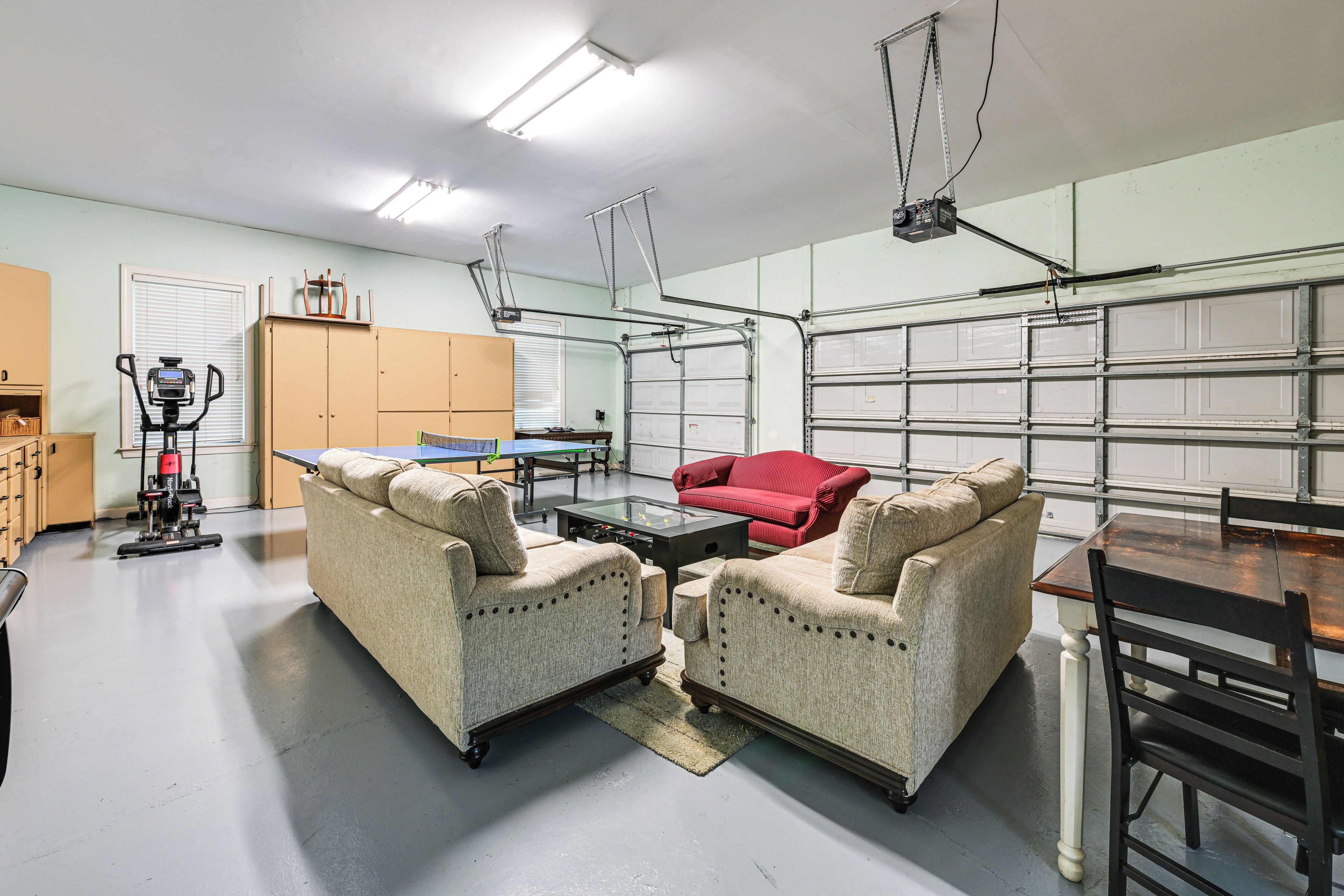 A spacious garage with two upholstered chairs, a red sofa, and a table.