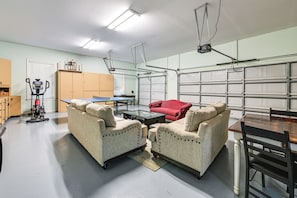 A spacious garage with two upholstered chairs, a red sofa, and a table.