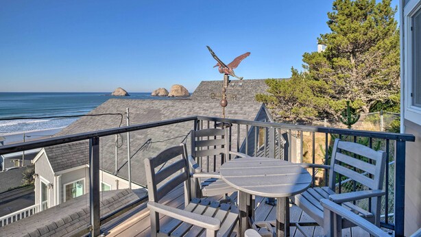 A balcony with a table and chairs overlooking a beach with rocks and a clear sky. - Exquisite Oceanside House w/ Pacific Views & Deck! (Tillamook)
