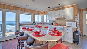 A modern kitchen with a large island, white cabinets, and a view of the ocean. - Exquisite Oceanside House w/ Pacific Views & Deck! (Tillamook)