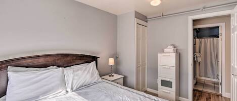 A bedroom with a bed, nightstand, dresser, and a door leading to a bathroom.