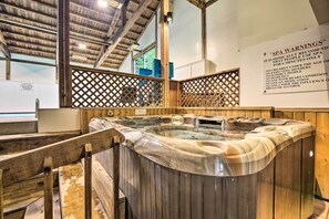 Un espace bien-être comprenant un jacuzzi, des poutres en bois et un panneau affichant les consignes de sécurité.