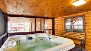 A wooden cabin with a hot tub, wooden walls, and a window overlooking a yard. - Broken Bow Abode w/ Hot Tub < 7 Mi to Lake! (Broken Bow)