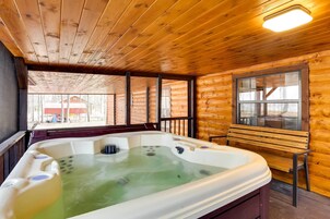 Una cabaña de madera con jacuzzi, paredes de madera y una ventana con vistas a un jardín.