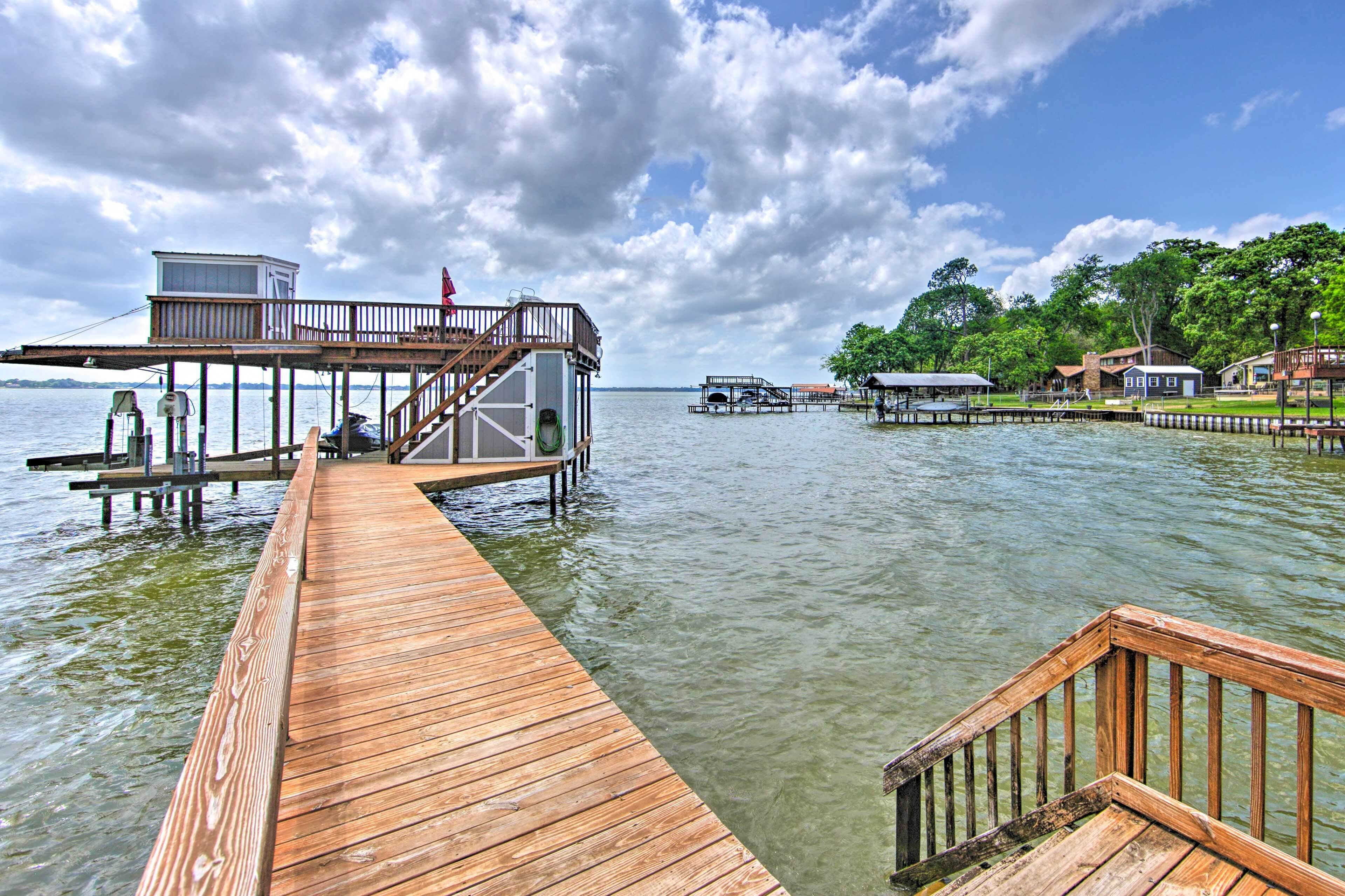 A wooden pier extending into calm water, with a small building and a covered area at the end.