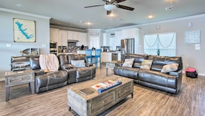 A spacious living room with leather sofas, a coffee table, and a dining area with blue chairs. - Private Dock & Boat House: Lakefront Mabank Home (Mabank)