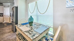 A kitchen with white cabinets, a stainless steel refrigerator, a dining table with a blue placemat, and a decorative vase. - Private Dock & Boat House: Lakefront Mabank Home (Mabank)