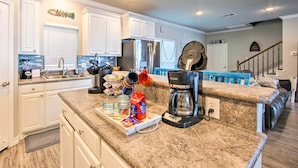 A modern kitchen with white cabinets, a stainless steel refrigerator, a coffee maker, and a breakfast bar. - Private Dock & Boat House: Lakefront Mabank Home (Mabank)